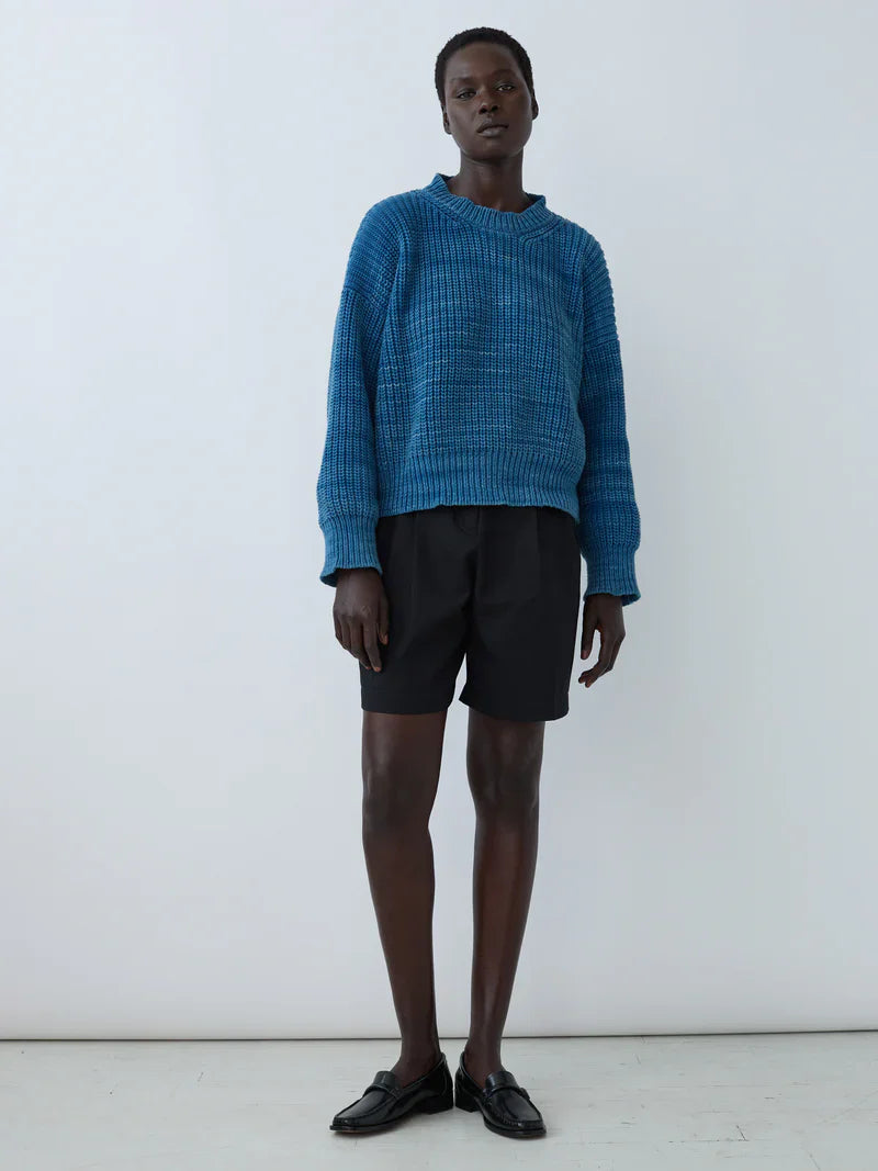 Model wearing a relaxed-fit blue sweater and black Bermuda Boy Shorts by Shaina Mote, showcasing modern, structured style.