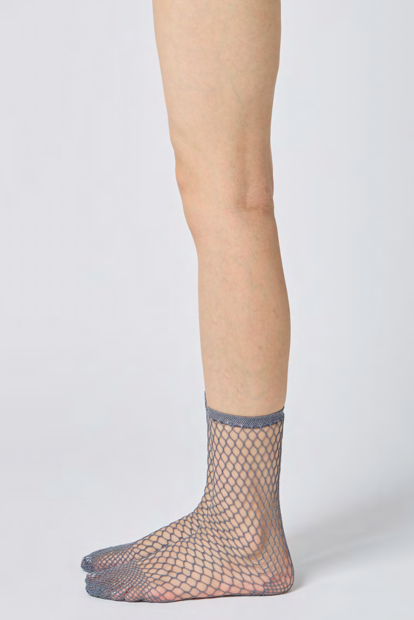 Fishnet socks worn by a person on a plain background