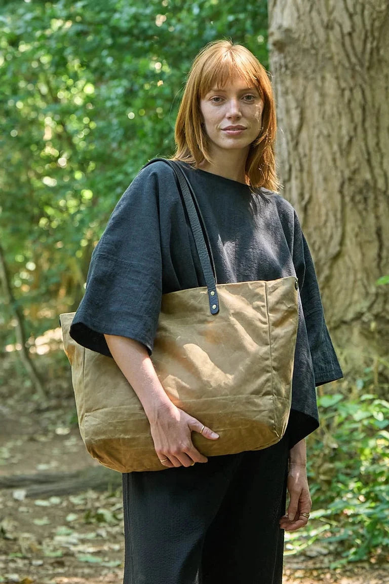 Woman holding a brown tote bag in a forest setting