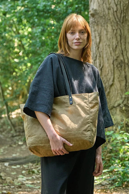 Woman holding a brown tote bag in a forest setting