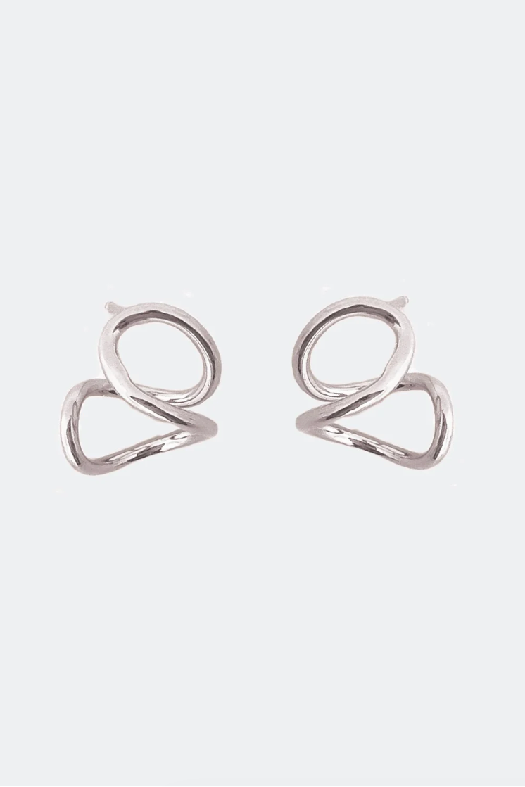 A pair of minimalist silver-toned geometric hoop earrings with a twisted, open heart-like design, displayed on a clean, light gray background.